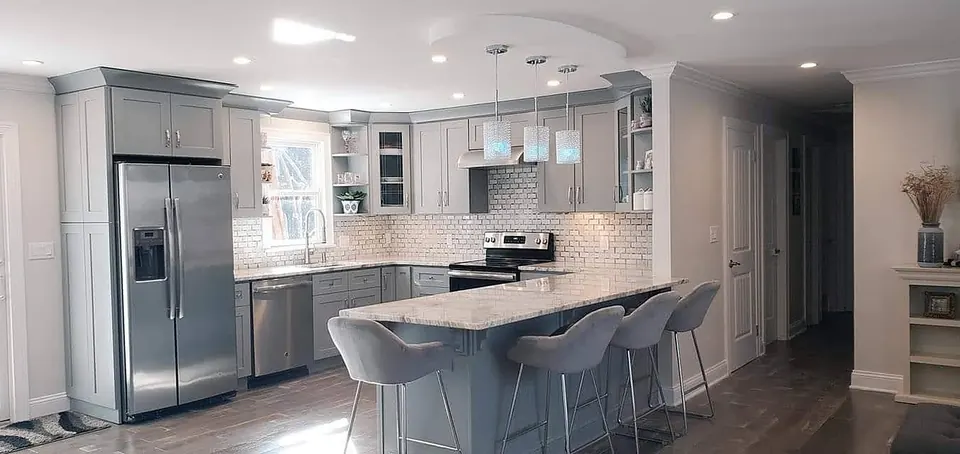 Gray shaker kitchen with granite peninsula and pendant lights by Dream Kitchen Designs